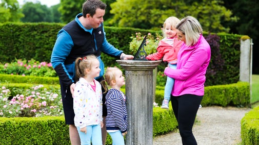 A family of five have stopped to admire the sundial in the rose garden